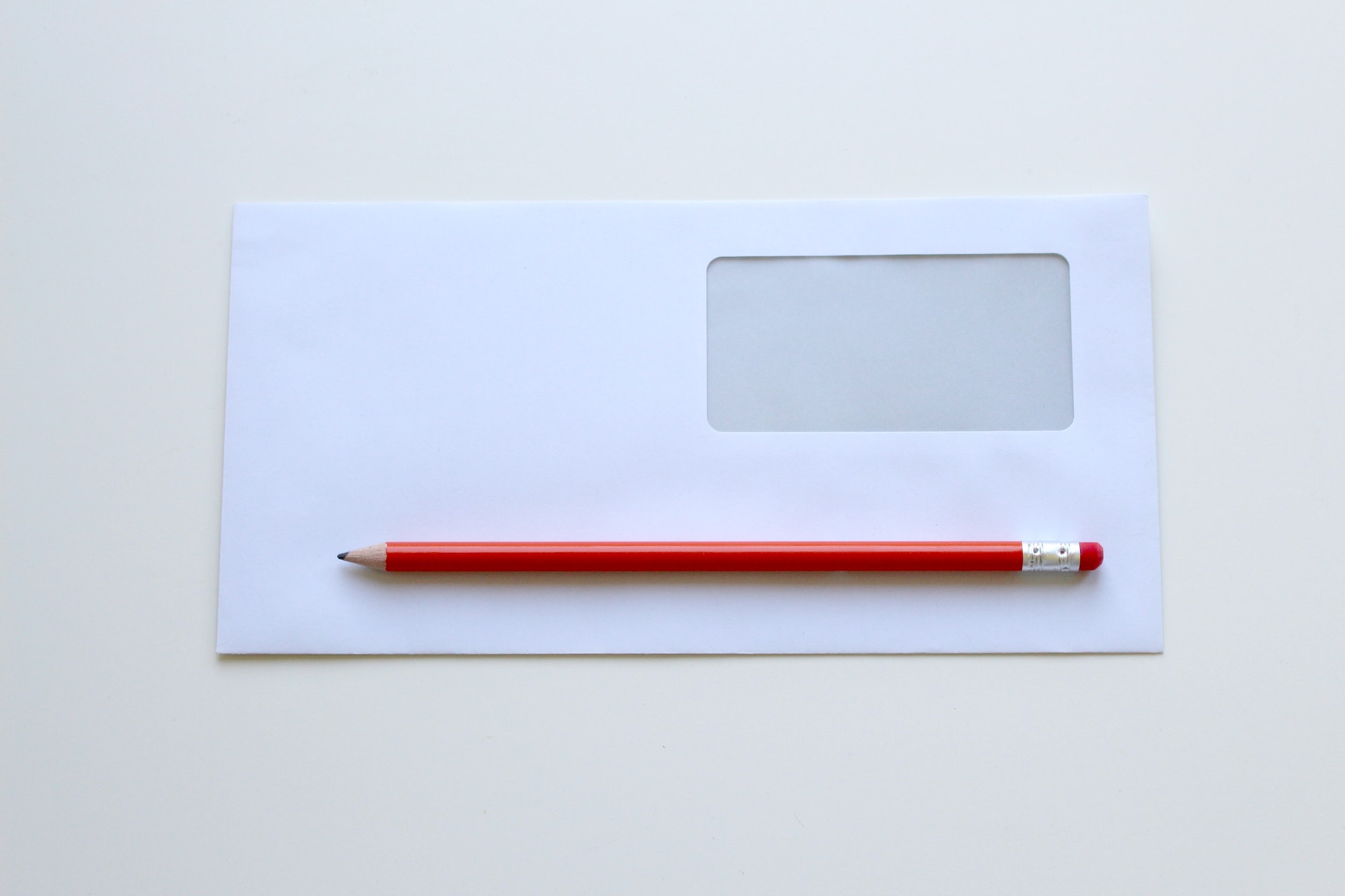 A white envelope with a red pen on top of it