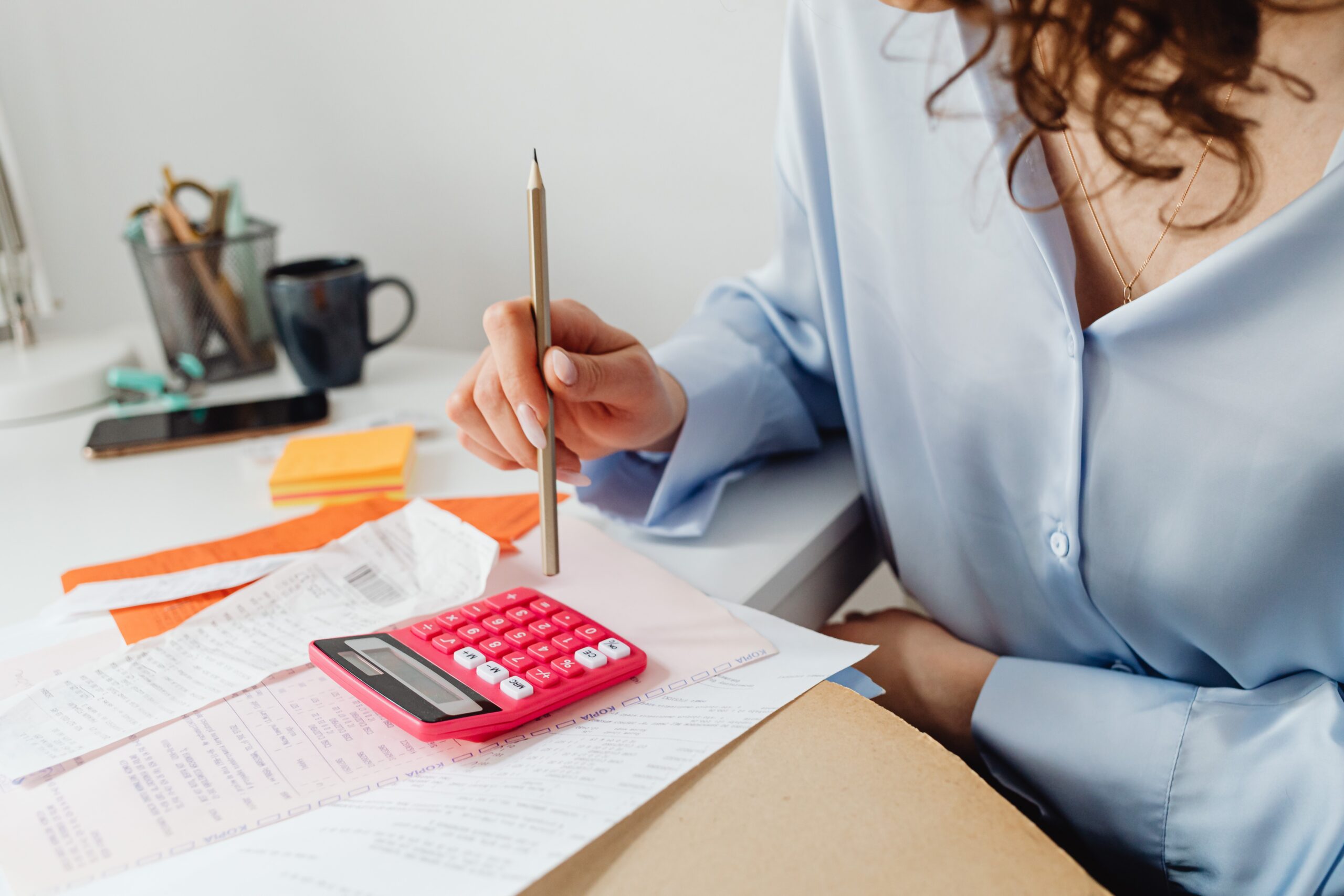 Woman doing calculations on the table with a pile of bills