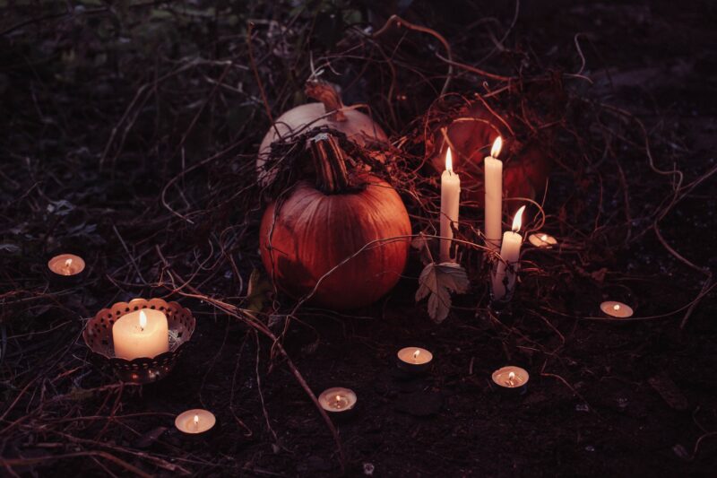 Pumpkins and candles clustered on grass - simple DIY decorations are an easy way to save at Halloween