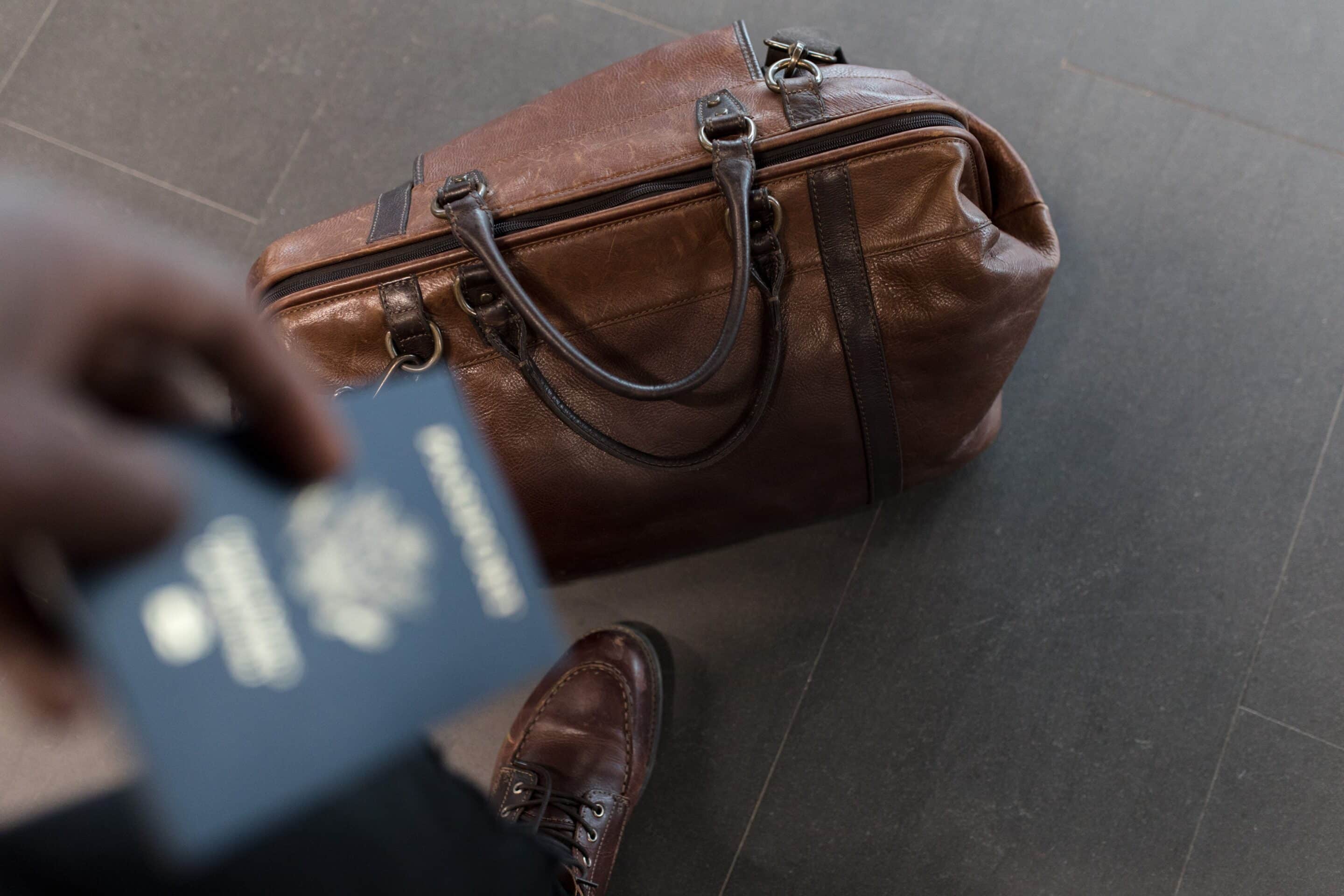 Person ready to move away with a suitcase on the floor and passport in hand