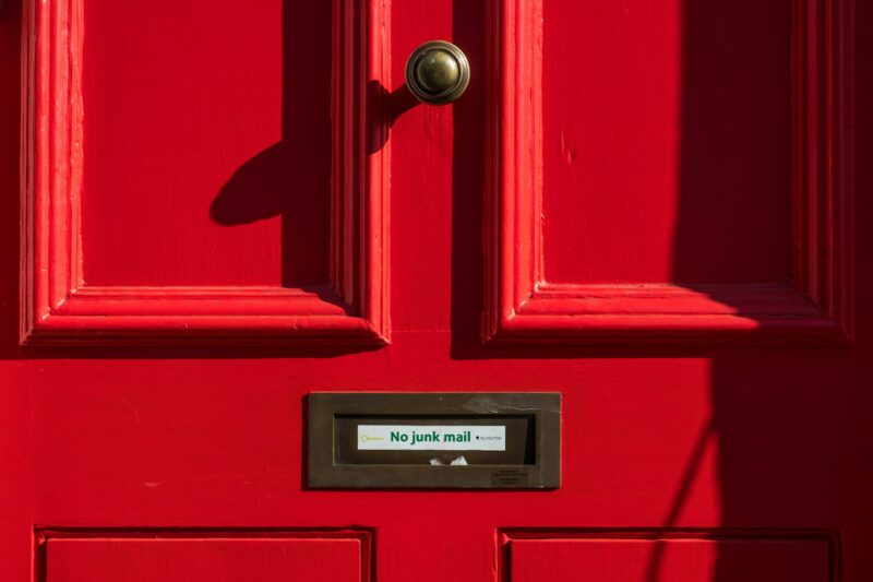 A letterbox in a red front door with a 'no junkmail' sign